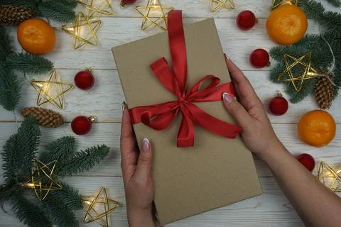 In women's hands, a gift in craft paper with a red bow Stock Photos