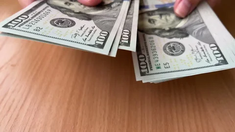 Women's hands hold and count dollars over a wooden table Stock Footage 220732413