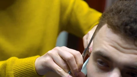 Women's hands hold a black comb and cut men's curly hair with iron scissors. 库存影片 127701706