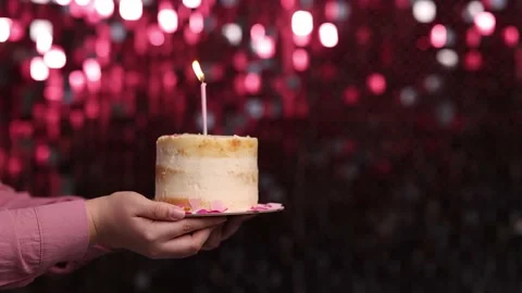 Women's hands hold a cake with a candle Stock Footage 229648602
