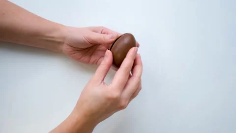 Women's hands hold a chocolate egg breaks it in half and finds a wedding ring Stock Footage 169759296