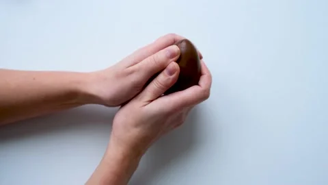 Women's hands hold a chocolate egg breaks it in half Video stock 169759319