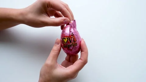 Women's hands hold a chocolate egg love surprise open foil wrapper Stock-Footage 169759355