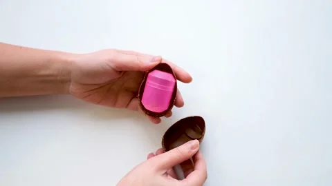 Women's hands hold a chocolate egg breaks it in half and takes out a wedding Stock-Footage 169759375