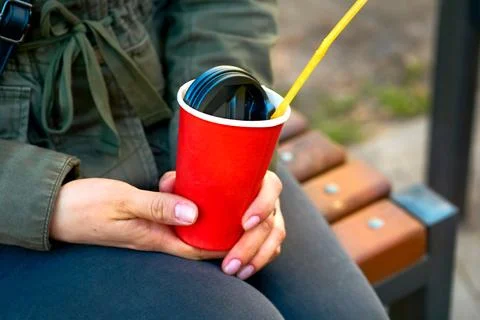 Women's hands hold an empty red paper plastic glass for drinks, coffee, tea Stock Photos