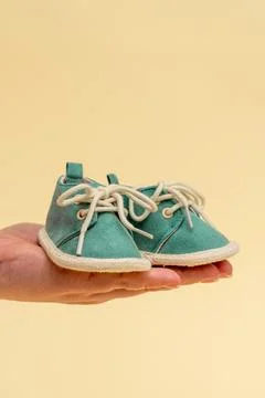 Womens hands hold a pair of tiny childrens shoes. As a symbol of motherhood and Stock Photos