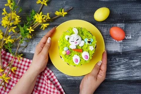 Women's hands hold a plate with an Easter cake Stock Photos