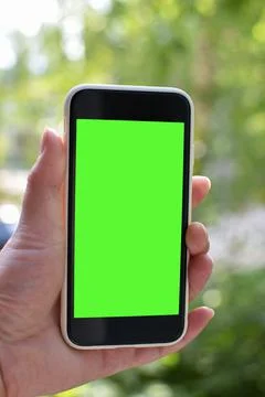Women's hands hold a smartphone with an empty screen in nature. Chromakey. Place Foto stock
