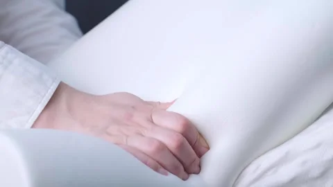 Womens hands holding memory foam pillows, showcasing quality sleep support for o Stock Footage 299722188