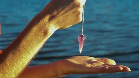 Women's hands holding a pendulum with a lake in the background Stock Footage 252135593