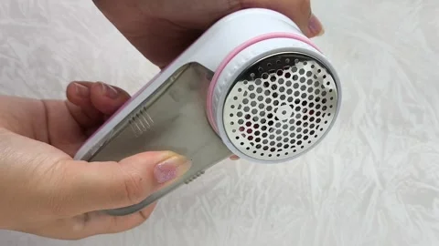 Womens hands include an Anti-pilling razor. Removing pellets from clothes using Stock Footage 316202759