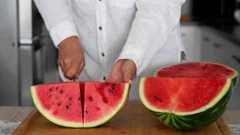 Women's hands in the kitchen cut a large ripe watermelon with Stock Footage 290983591