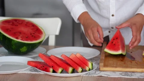 Women's hands in the kitchen cutting a large ripe watermelon Stock Footage 290983942