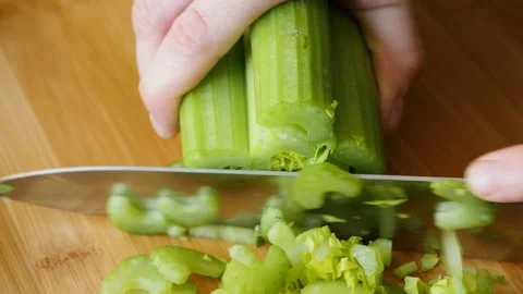 Women's hands with a knife cut celery on a wooden board Stock Footage 178483741