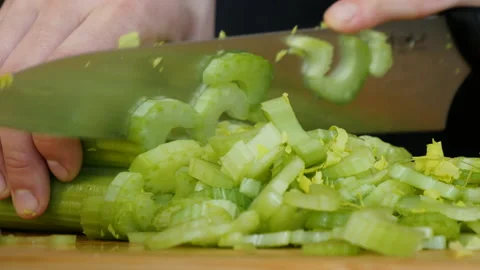 Women's hands with a knife cut celery on a wooden board Stock Footage 178483978