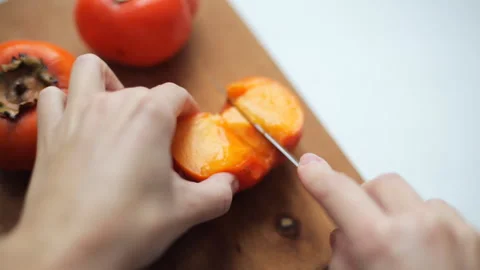 Women's hands with a knife cut persimmon Video stock 101284884