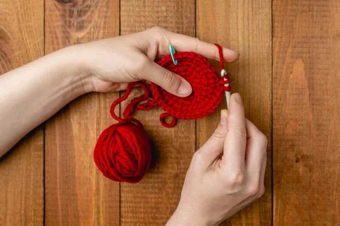 Women's hands knit on the spokes a pattern of soft acrylic yarn of red color Stock Photos