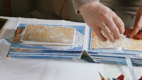 Women's hands leafing through the pages of the scrapbooking photo album Stock Footage 106465847