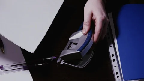 Women's hands make holes in sheets of paper with a hole punch Stock Footage 103163929