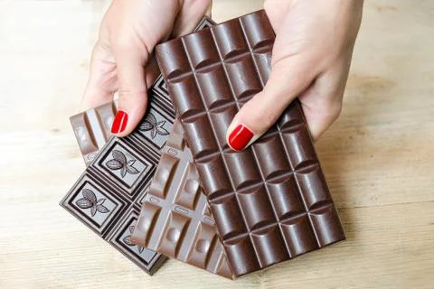 Women's hands, offering a choice of different chocolate bars. Stock Photos