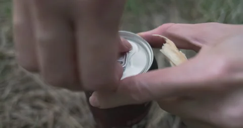 Women's hands open a can of beer standing on the grass. Side view from above Stock Footage 204934313