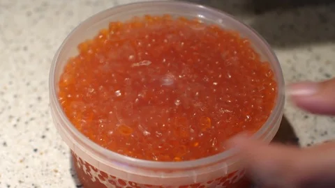 Women's hands open the package with selected red caviar. Plastic jar with red Stock Footage 119352497