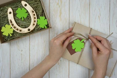 Women's hands pack a gift for St. Patrick's Day Stock Photos