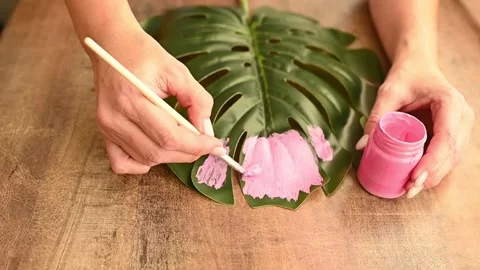 Women's hands paint a plastic palm leaf with pink paint. Stock Footage 229411568