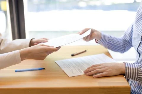 Women's hands pass signed documents to each other. Stock Photos