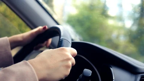 Women's hands in a pink coat on the steering wheel of the car. woman driving a Stock Footage 107841849