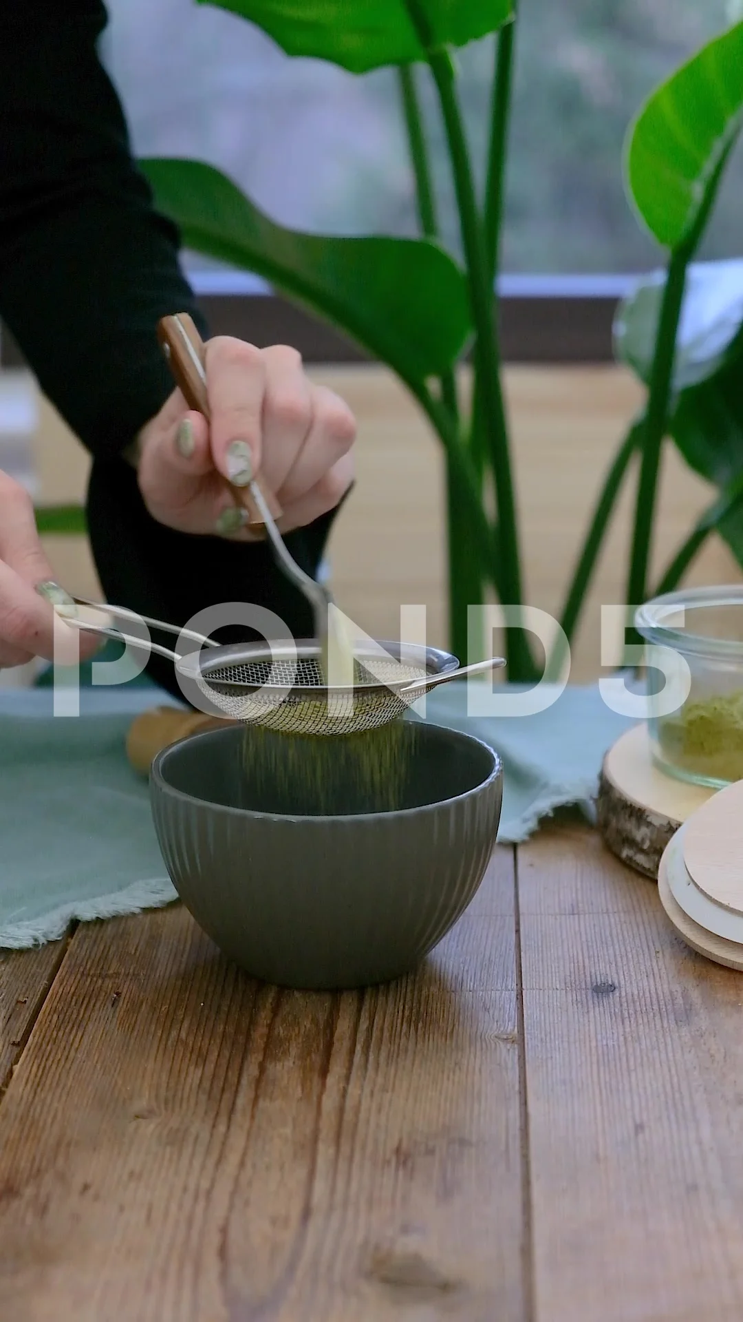 Female barista hands preparing matcha tea on a bowl, mixing it