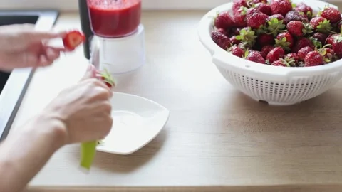 Women's hands process strawberries. Preparing strawberries for grinding in a Stock Footage 220773586