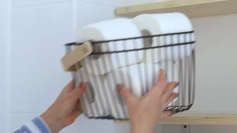 Women's hands put a basket with white toilet paper on the shelf. Stock Footage 236964385