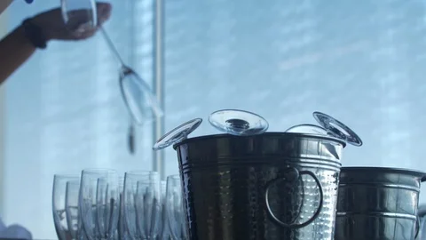 Women's hands put clean transparent glasses in a metal champagne bucket Stock Footage 109143494
