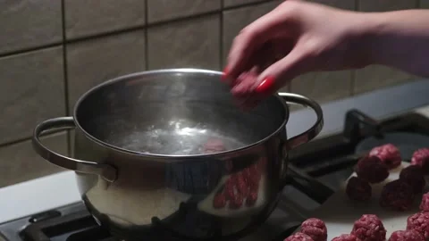 Women's hands put meatballs in boiling water. Soup preparation process. Close-up Stock Footage 154998624