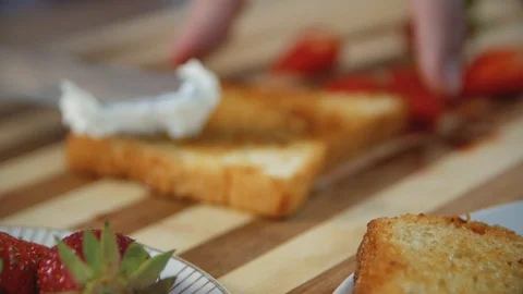 Women's hands putting cheese spread on a toasted white bread.  Strawberry san Stock Footage 108790156