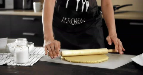 Women's hands roll out the dough with a rolling pin on a silicone mat Stock Footage 182345413