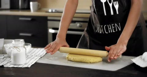 Women's hands roll out the dough with a rolling pin on a silicone mat Stock Footage 182347002