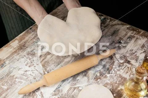 Women's hands rolling out the dough for homemade pizza Stock Photos