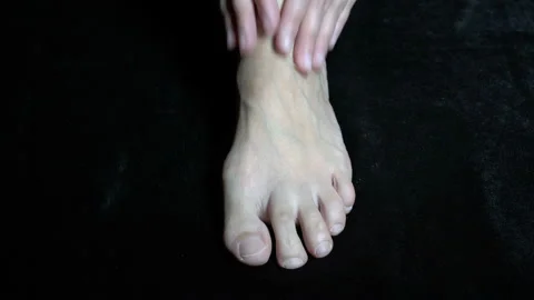 Women's hands rub their bare, numb feet against a black background. Close-up 스톡 동영상 149441330