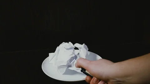 Women's hands set fire to a crumpled sheet of paper on a plate Stock Footage 102307209