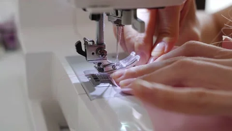 Women's hands sew one part of the pink fabric to another using a special white Stock Footage 201729906