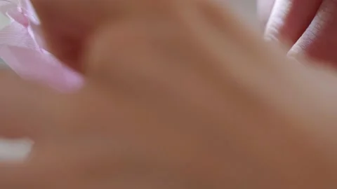 Women's hands sew one part of the pink fabric to another using a special white Stock Footage 201729916