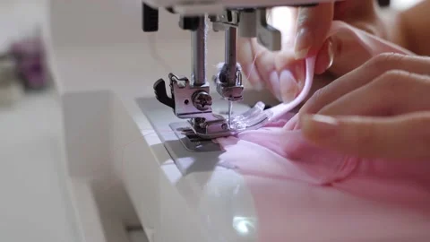 Women's hands sew one part of the pink fabric to another using a special white Stock Footage 201729922
