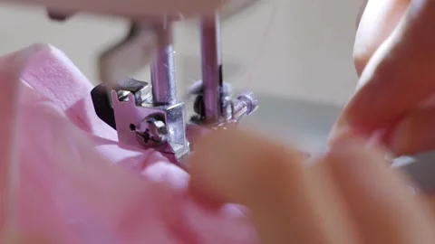 Women's hands sew one part of the pink fabric to another using a special white Stock Footage 201729933