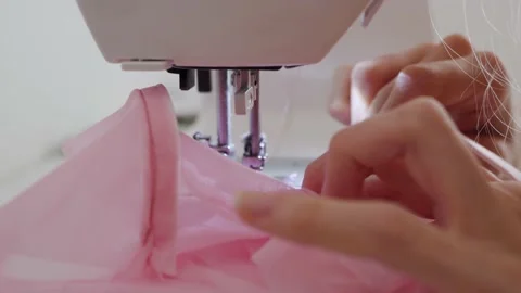 Women's hands sew one part of the pink fabric to another using a special white Stock Footage 201729939