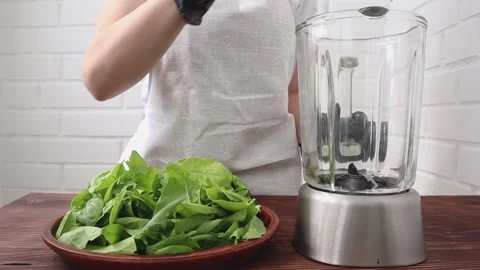 Women's hands shift fresh spinach into a blender for making smoothies. Vidéo 197844209