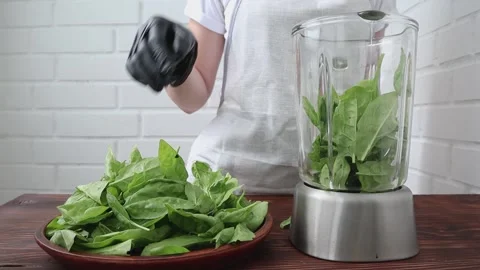 Women's hands shift fresh spinach into a blender for making smoothies. Vídeos de archivo 200785259