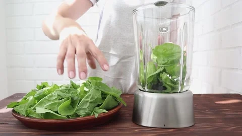 Women's hands shift fresh spinach into a blender for making smoothies. Vídeo Stock 202175399