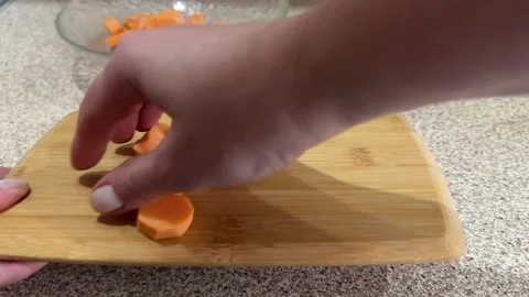 Women's hands shift the sliced sweet potato into a glass plate for further Stock Footage 254796028